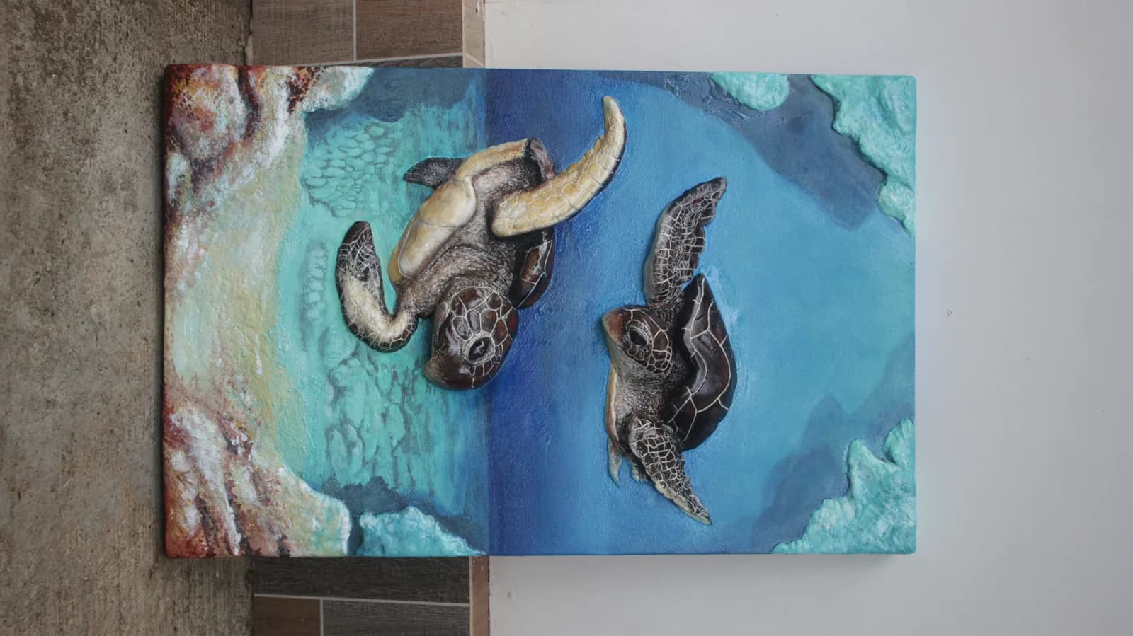 Two sea turtles painted over turquoise water, mounted on the wall