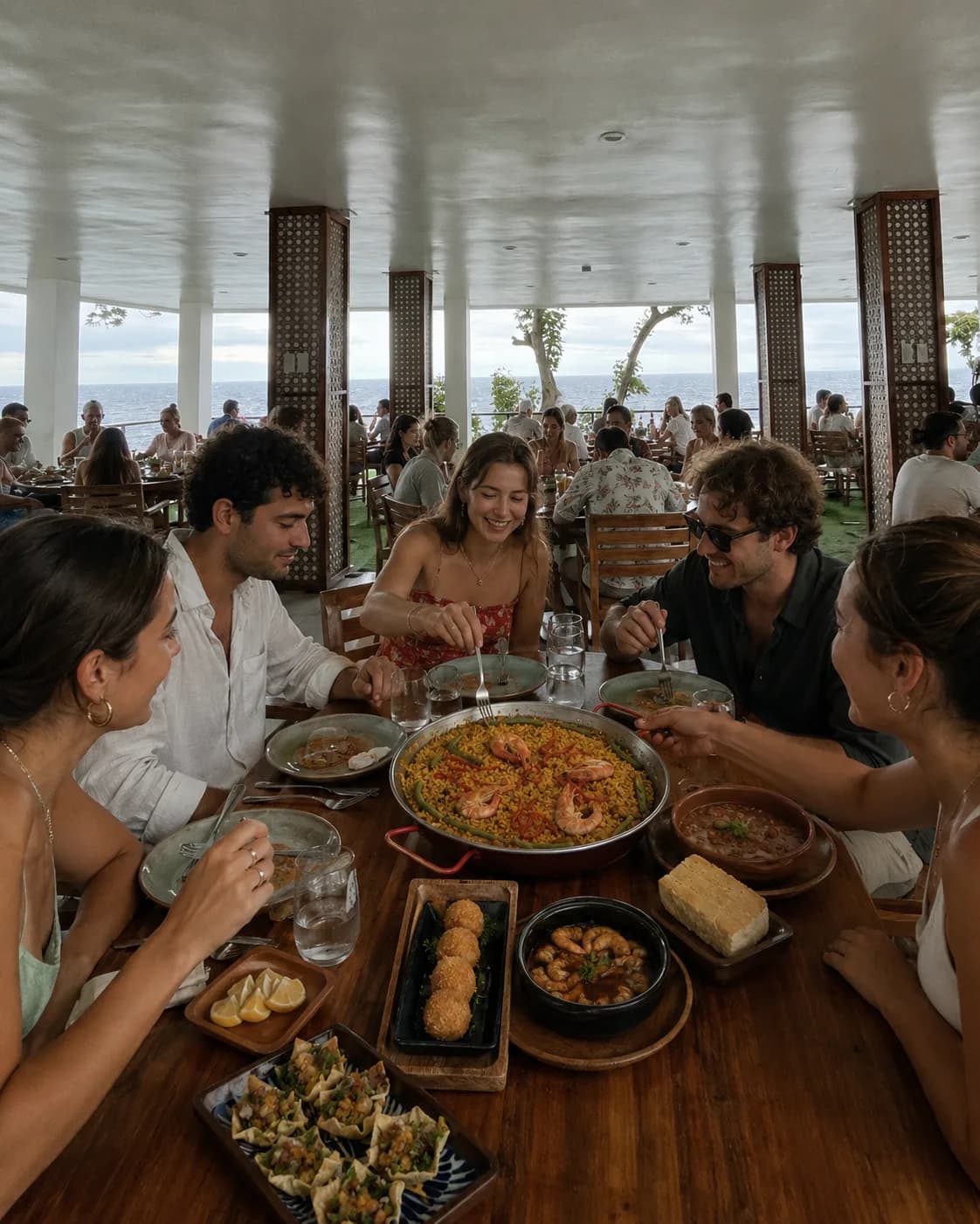 Guests sharing paella and tapas at a seaside table at Txaleta de Camiguin
