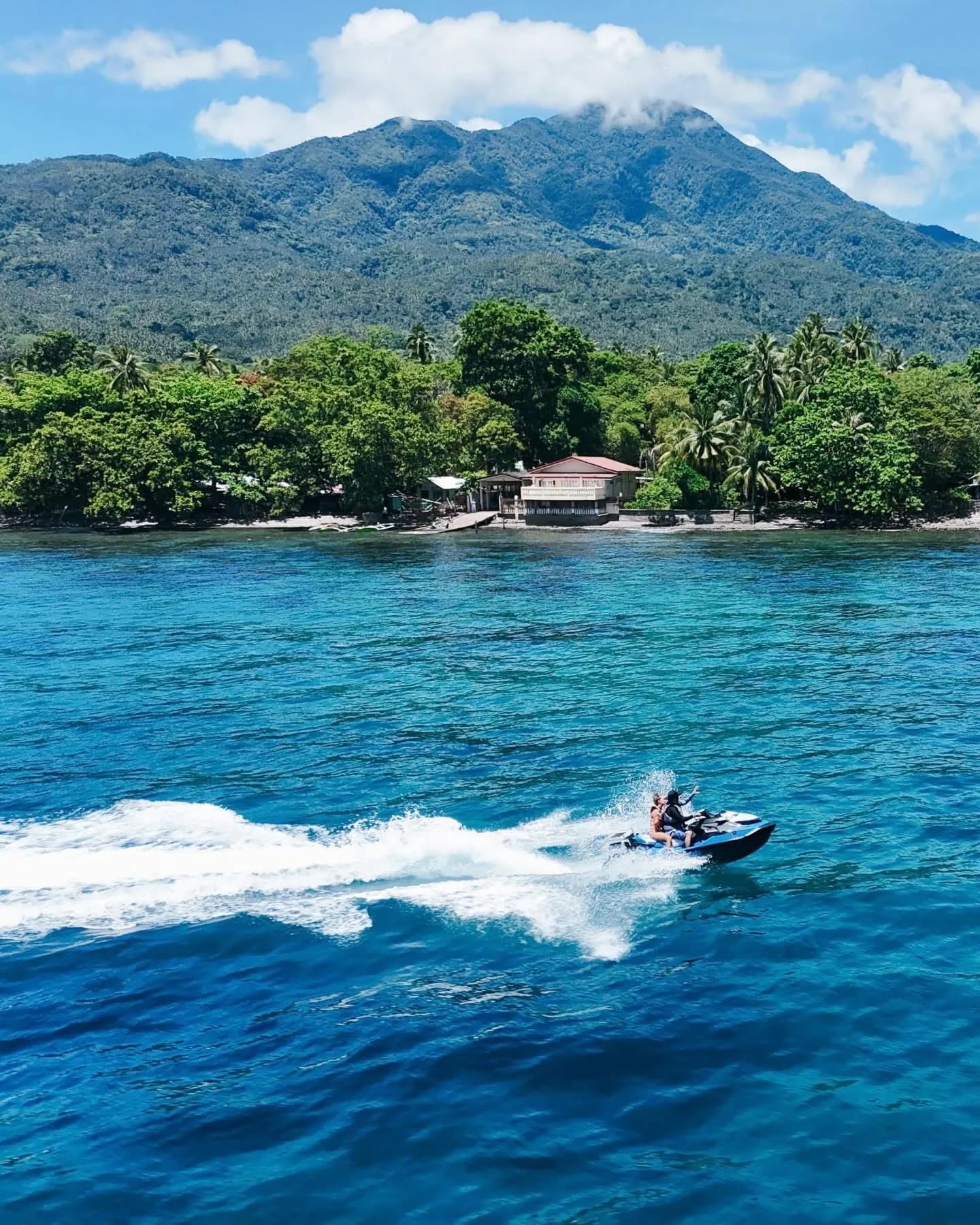 A jet ski cutting across the Bohol Sea below Mount Hibok-Hibok