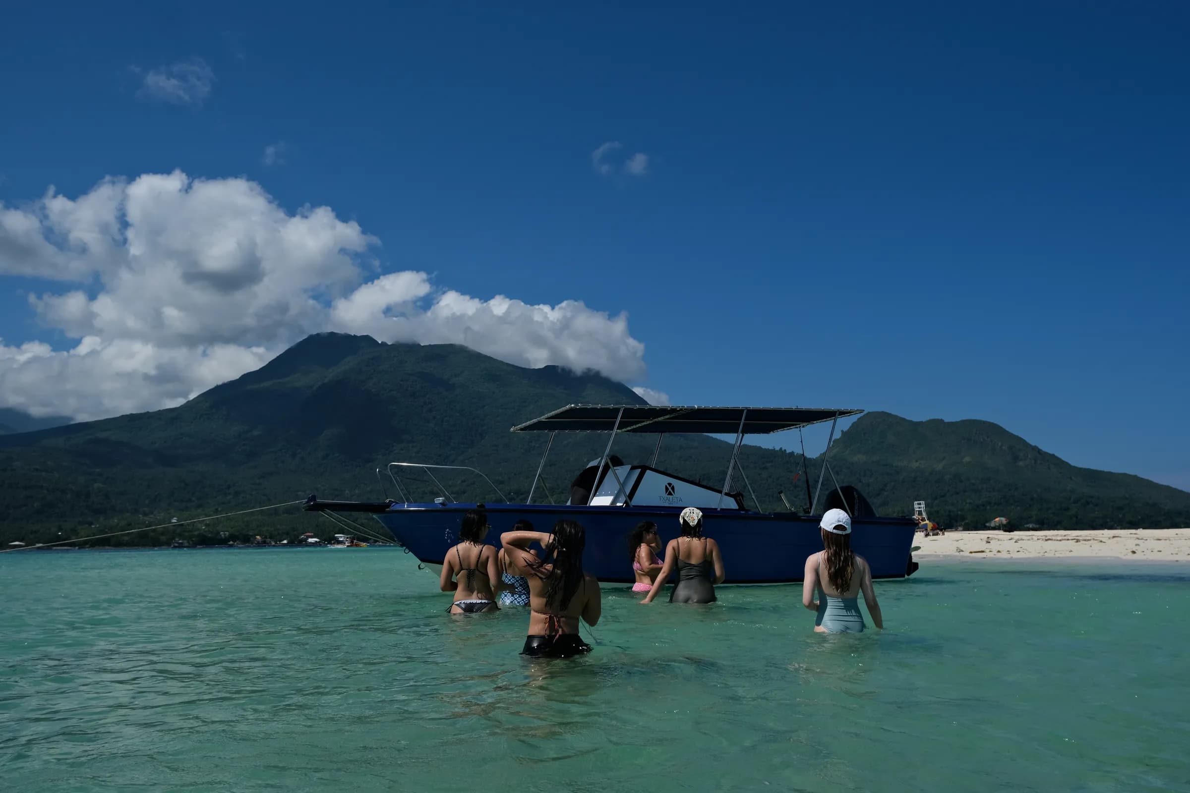 Guests on a Txaleta boat tour with Mount Hibok-Hibok rising behind them
