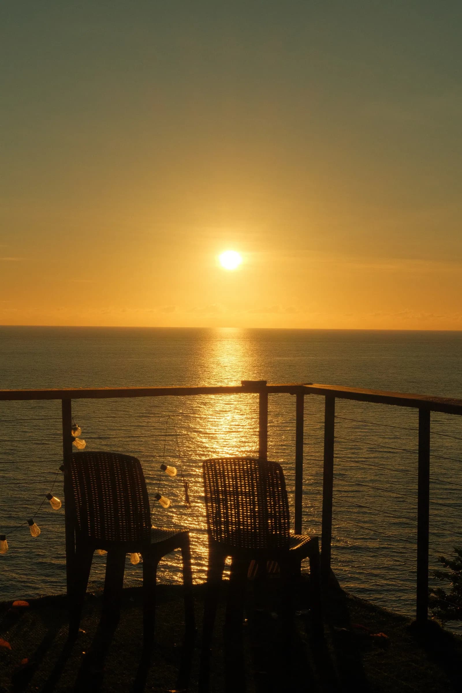 Two chairs facing the sunset over the Bohol Sea at Txaleta de Camiguin